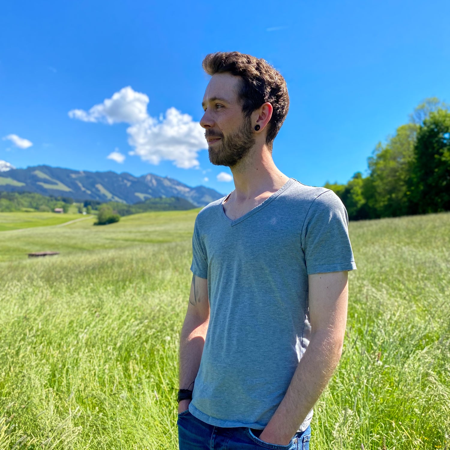 Lächelnder Dominik vor einer Berglandschaft.